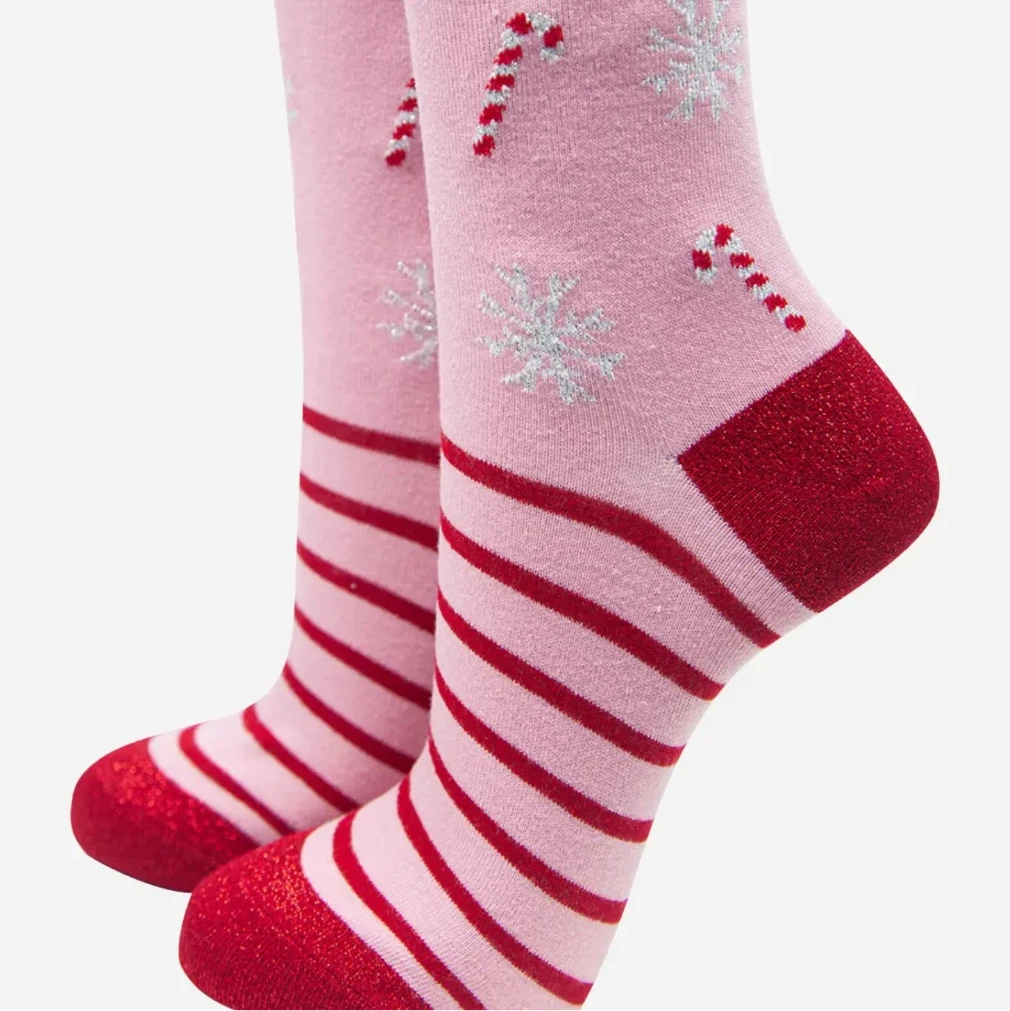 Pink socks with red and white stripes and snowflake designs on a white background