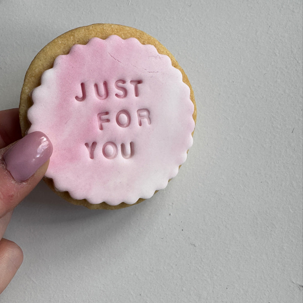 Handmade shortbread biscuit with royal icing onto in shade of pink, purple and white. stamped with the words just for you