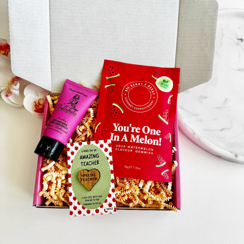 Thank you teacher gift box with watermelon gummies with you're one in a melon written on them, a pink tube of hand cream and a pocket hug token with a hug for an amazing teacher engraved