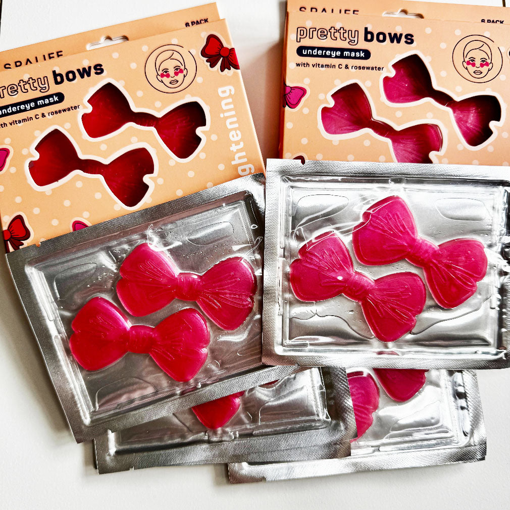 Pink bow-shaped (face masks) in silver packaging with 'pretty bows' packaging on a white background.