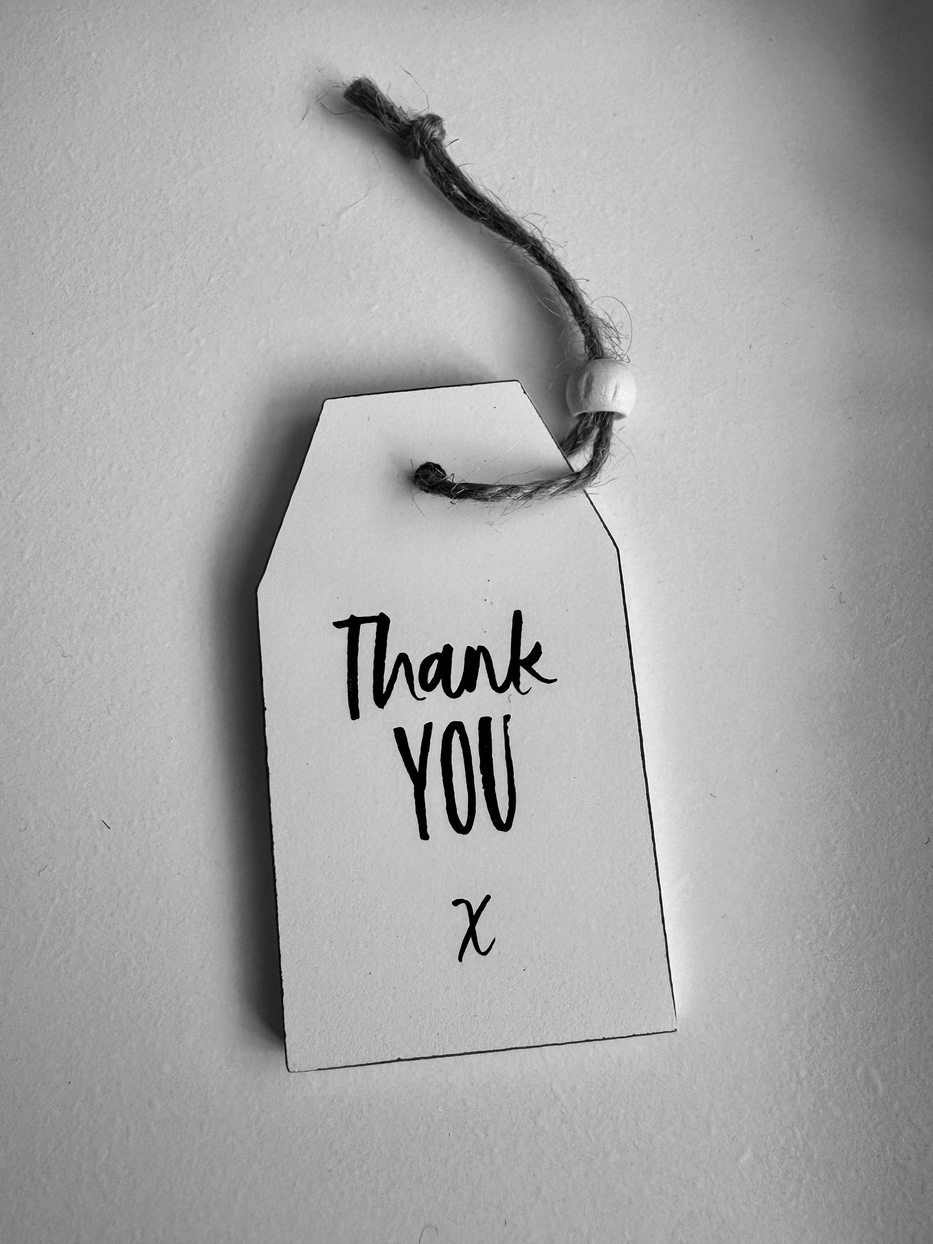 A small wooden tag-shaped sign perfect for adding to a 'thank you' gift. Features text that reads, 'Thank you' and finished with a wooden bead.
