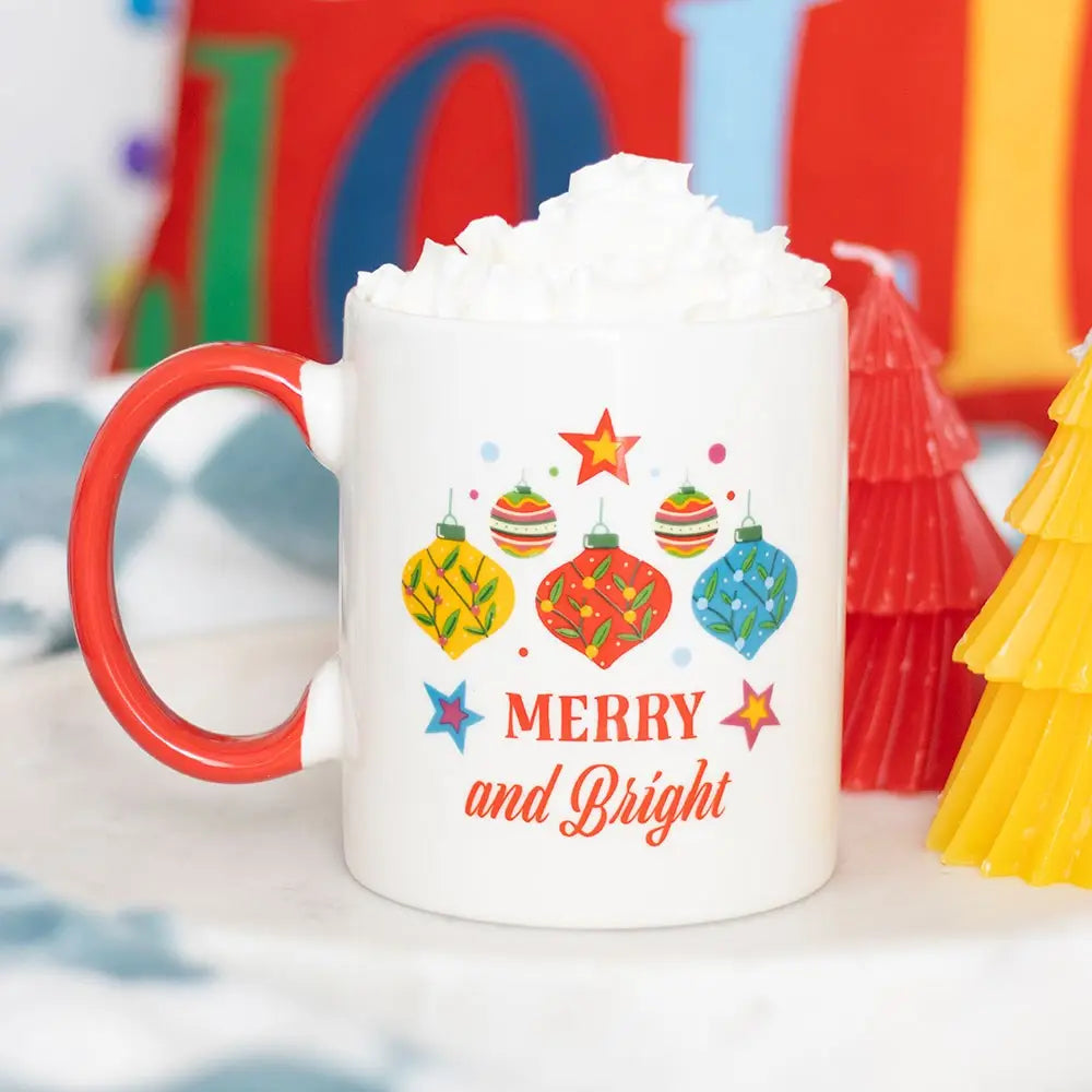 white mug with a red handle and bauble design that says merry and bright