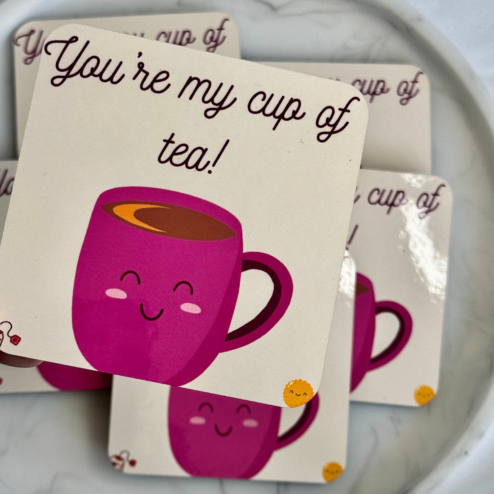 Cream coaster showing a pink smiling cup with the words you're my cup of tea