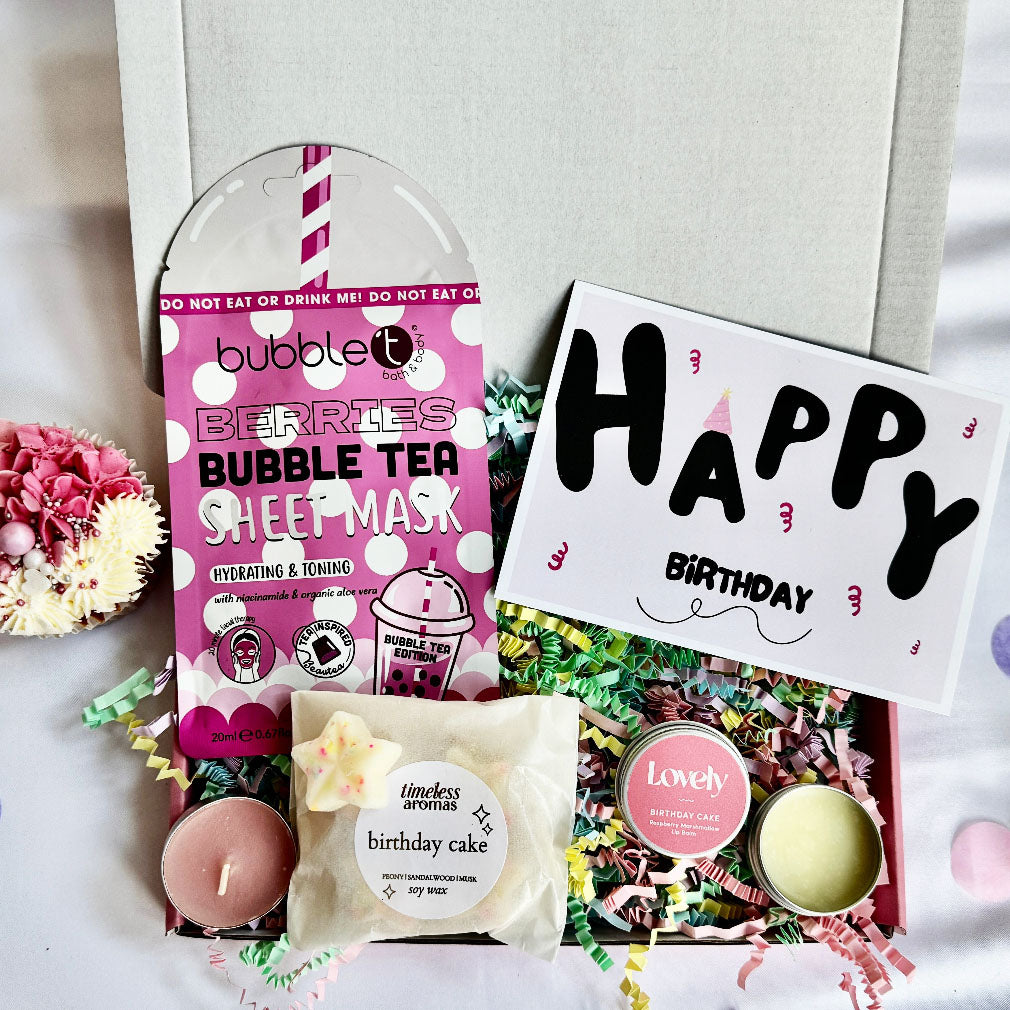 Birthday-themed gift set with bubble tea sheet mask, candle, and 'Happy Birthday' card on a light background.