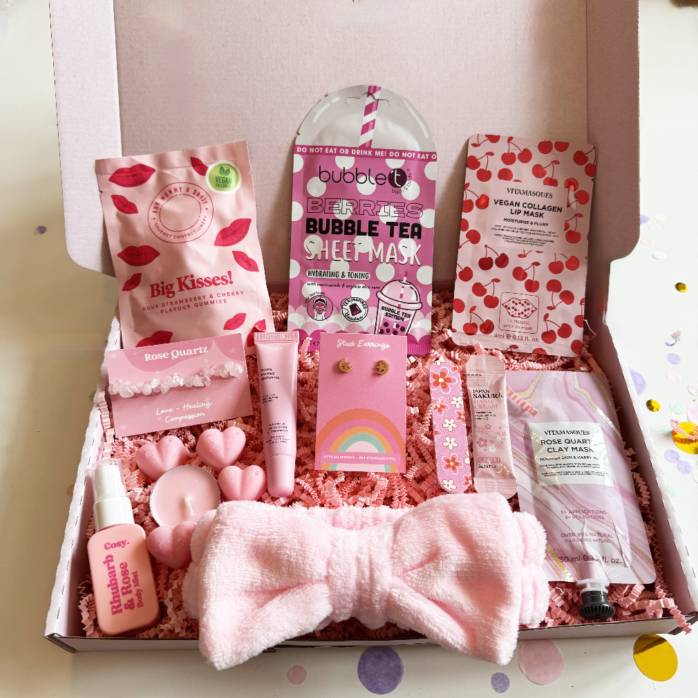 Pink-themed care package with various items including a bow, lip mask, and skincare products.