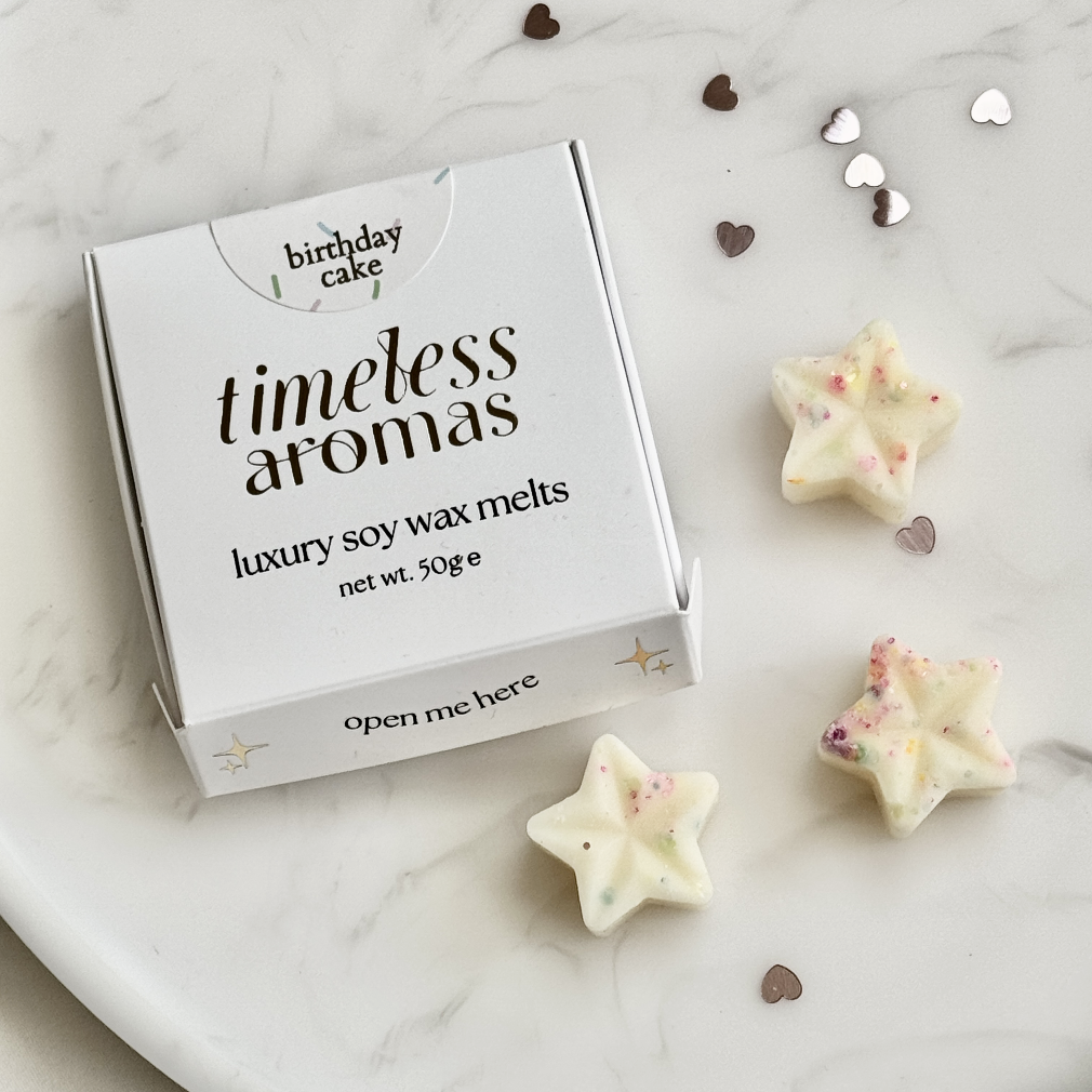 Box of Timeless Aromas luxury soy wax melts with star-shaped melts on a marble surface.