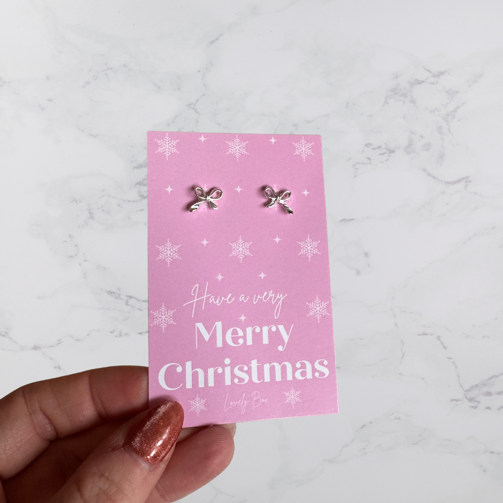 Pink card with Christmas-themed earrings and 'Have a very Merry Christmas' text.