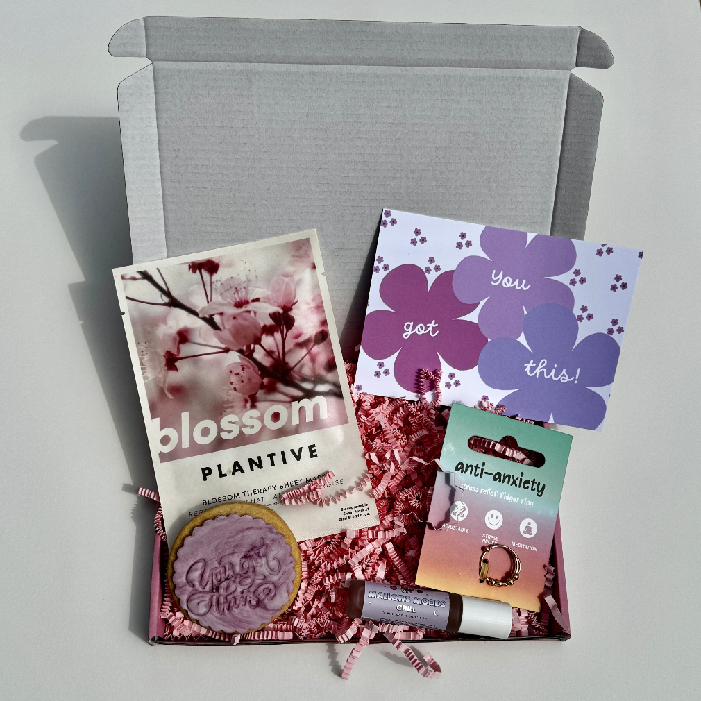 Encouragement gift box with “you got this” biscuit, anti-anxiety ring, blossom face mask, and chill roller balm – ideal for stress relief and self-care.