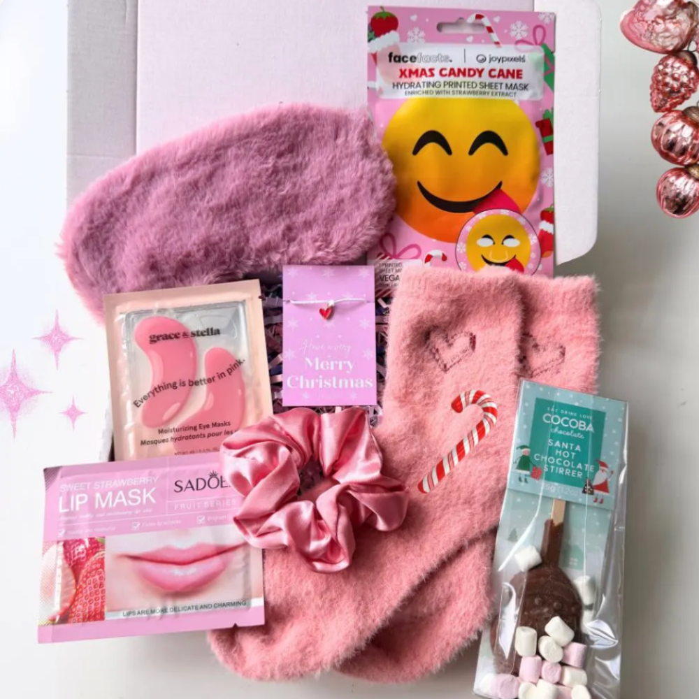 Pink Christmas Eve pamper gift box for her with fluffy socks, sleep mask, satin scrunchie, face masks, hot chocolate stirrer and Christmas wish bracelet.