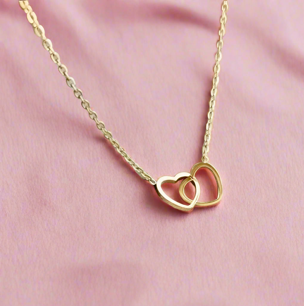 Playful gold necklace with two linked heart charms on a shiny chain, perfect for a fun and meaningful gift.