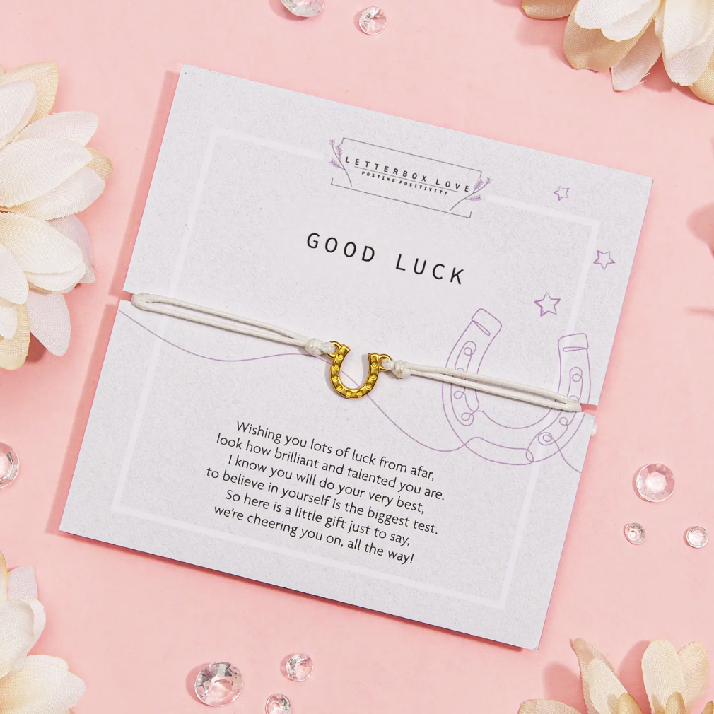 Good luck card with gold horseshoe charm on a pink background