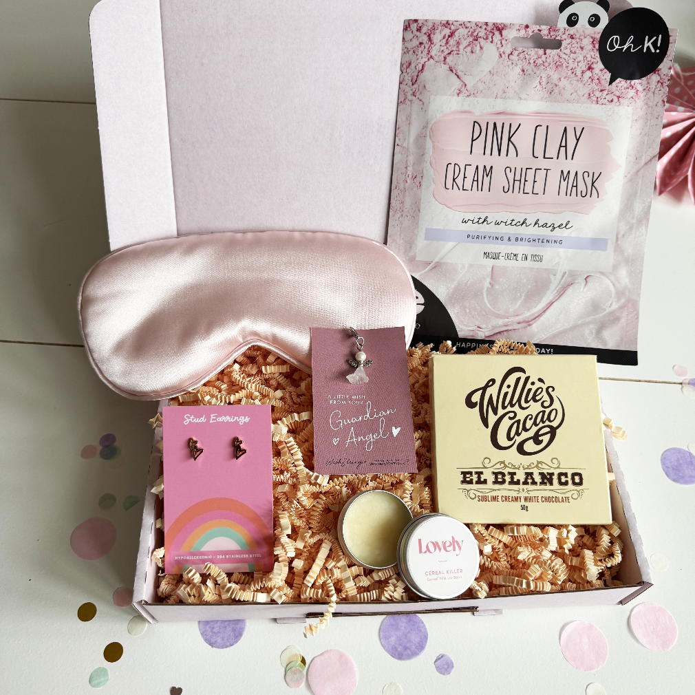 Gift box with pink sleep mask, earrings, and skincare products on a light background