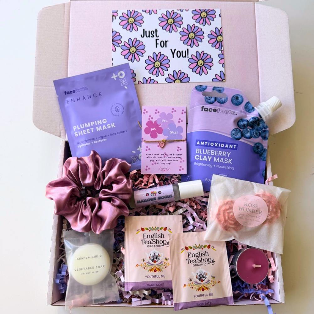 Luxury pink pamper gift box featuring a plumping sheet face mask, blueberry clay mask, handmade wax melt, satin scrunchie, English Tea Shop tea, chill roller oil, wish bracelet, vegetable soap and Just For You gift card, beautifully presented as a self care gift for her.