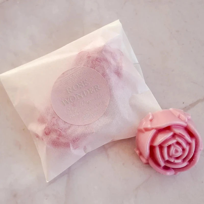 Pink rose-shaped soap bar next to a pink soap bar with 'Rose Wonder' label on a light background