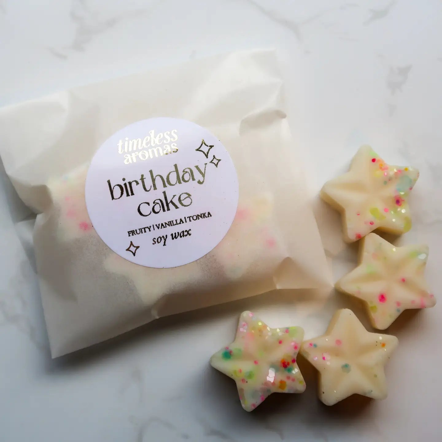Star-shaped birthday cake candles with a 'timeless aromas' label on a white background