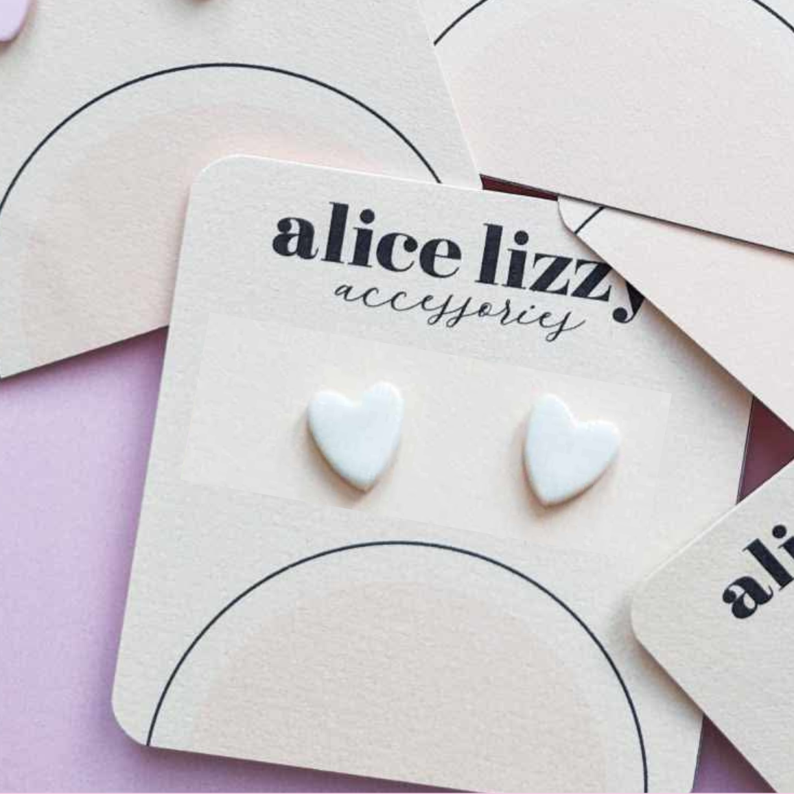 Heart-shaped earrings on a 'alice lizzy accessories' card with a pink background