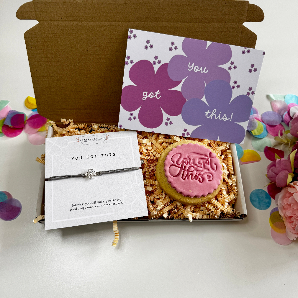 Gift set with cookie, bracelet, and card in a box on a white background