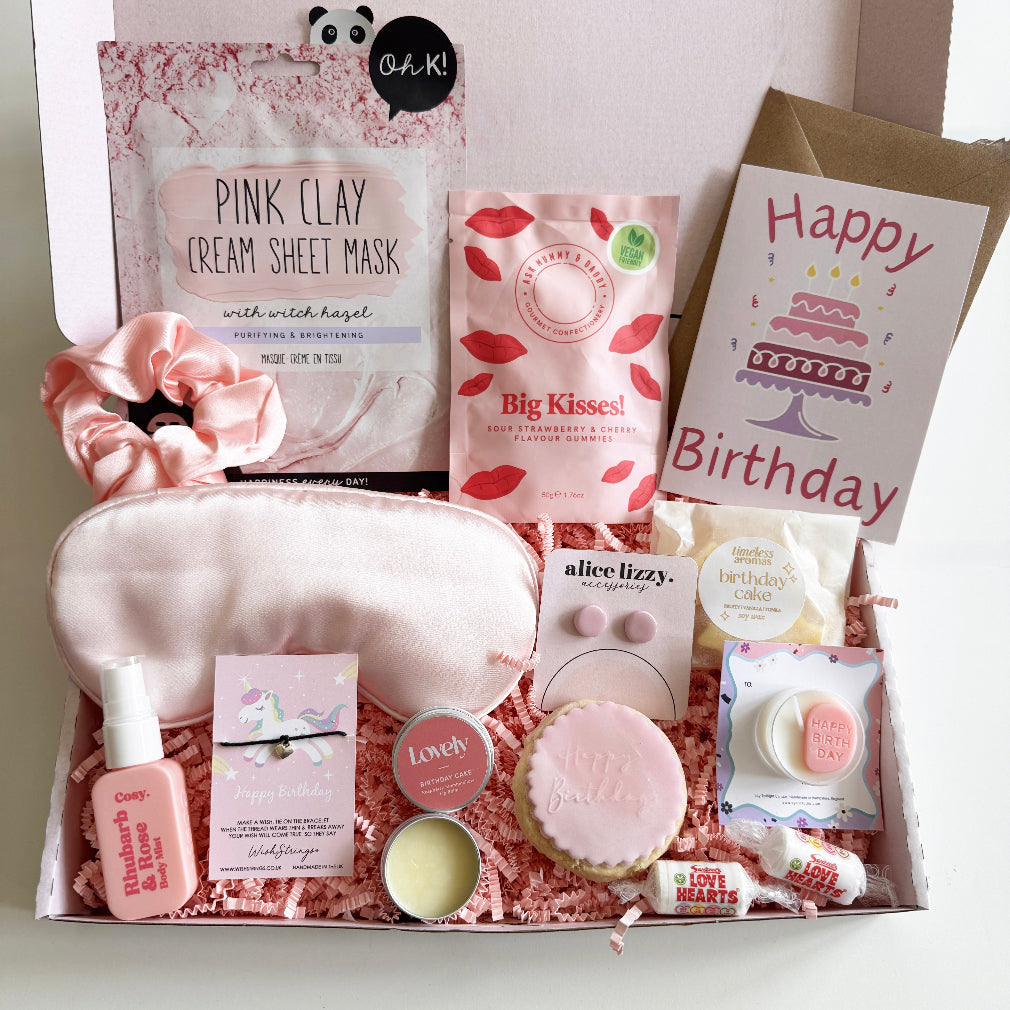 Birthday gift box with skincare products, a hairbrush, and a card on a white background