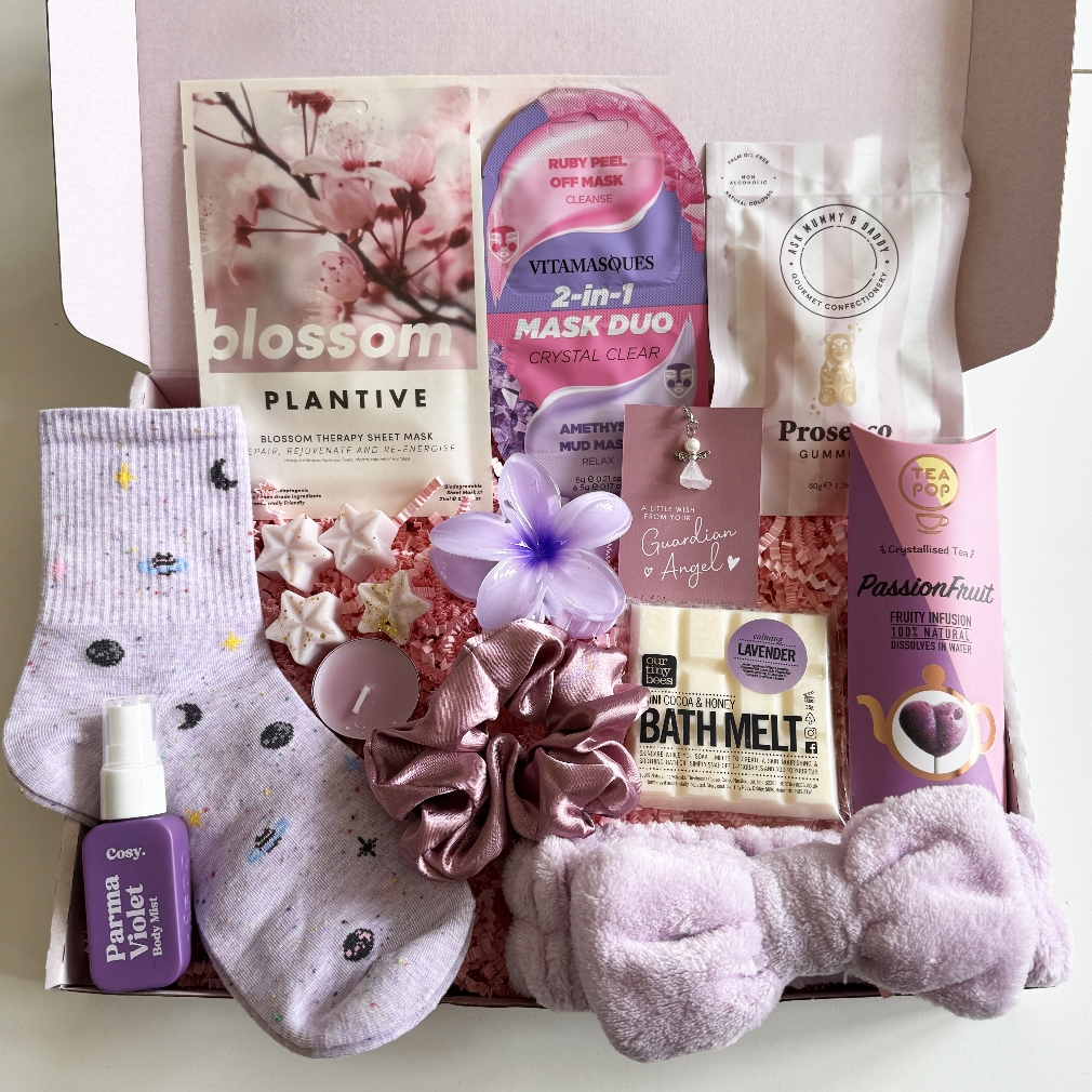 Gifting box with various items including socks, bath products, and a mask duo on a white background.