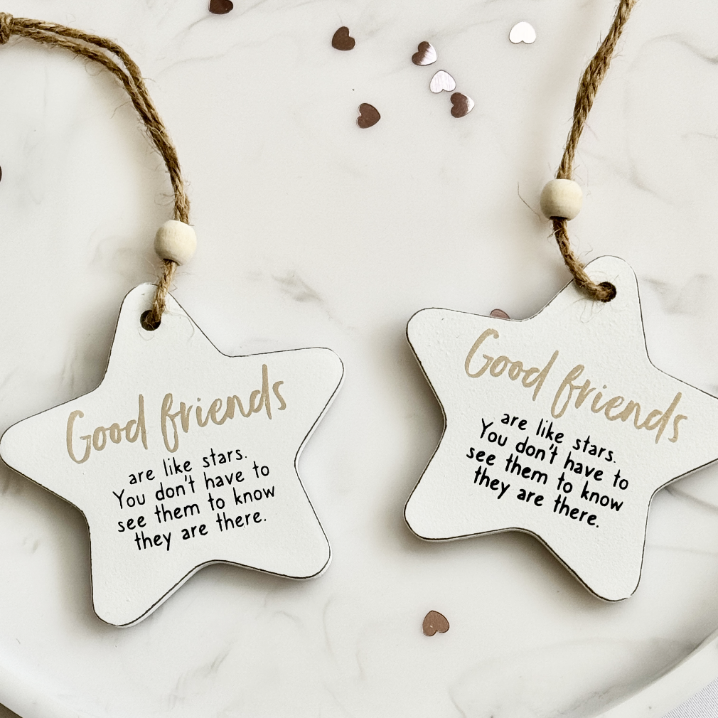 Two star-shaped ceramic decorations with 'Good friends are like stars' text on a marble surface.