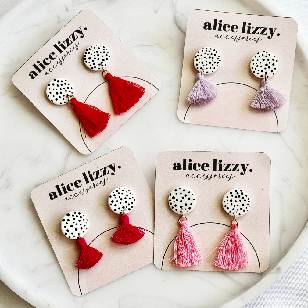 Four pairs of earrings on Alice Lizzy branded cards with red, pink, and purple tassels.
