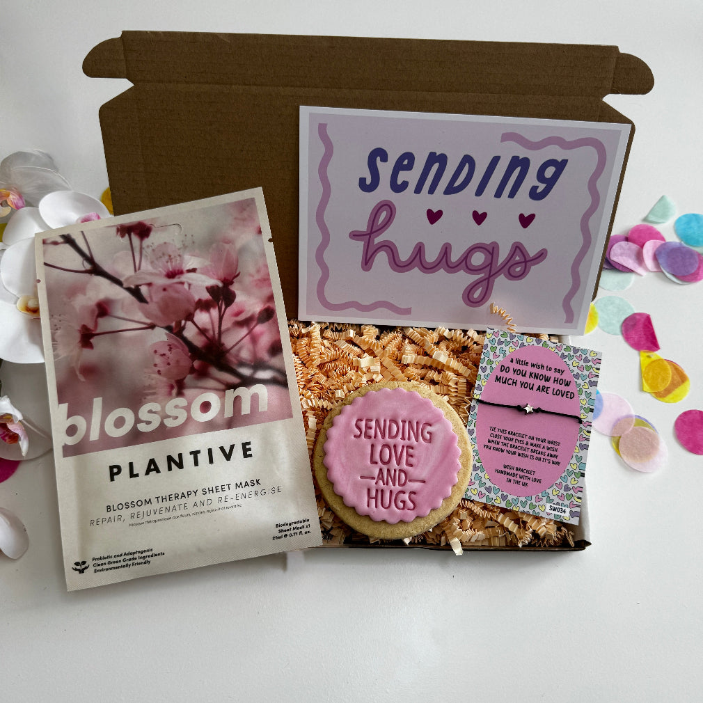 Motivational gift box with “So Proud of You” card, pink iced “You Got This” biscuit, rose quartz clay mask, and Loved so much wish bracelet, displayed in pink shredded paper with colourful confetti.