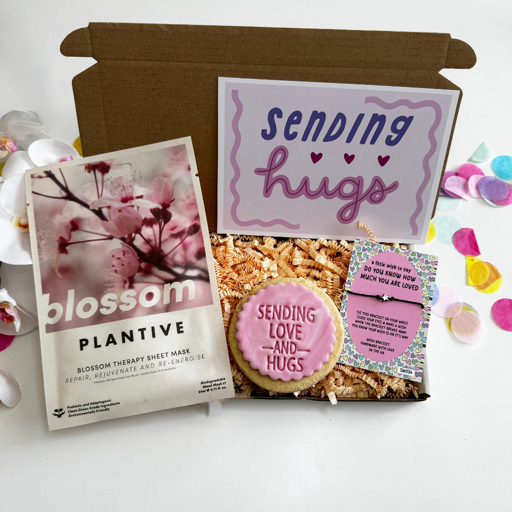 Product set with 'Sending Hugs' card, plant-based sheet mask, and cookie on a white background