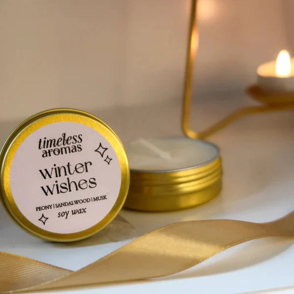 Candle with 'timeless aromas winter wishes' label on a soft background